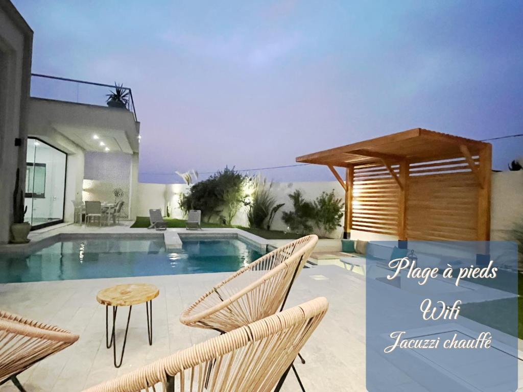 Villa Dar lynoute piscine sans vis à vis plage à pieds في تاجورميس: مسبح وكراسي وطاولة بجانب منزل