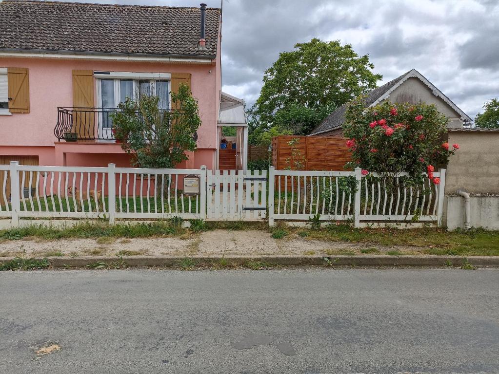 a white fence in front of a pink house at Maison de village in Saint-Loup