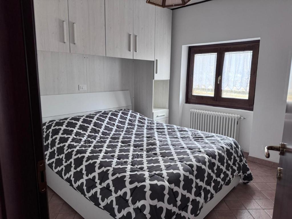 ein Schlafzimmer mit einer schwarzen und weißen Bettdecke auf einem Bett in der Unterkunft Casa Stefy in Mezzolago
