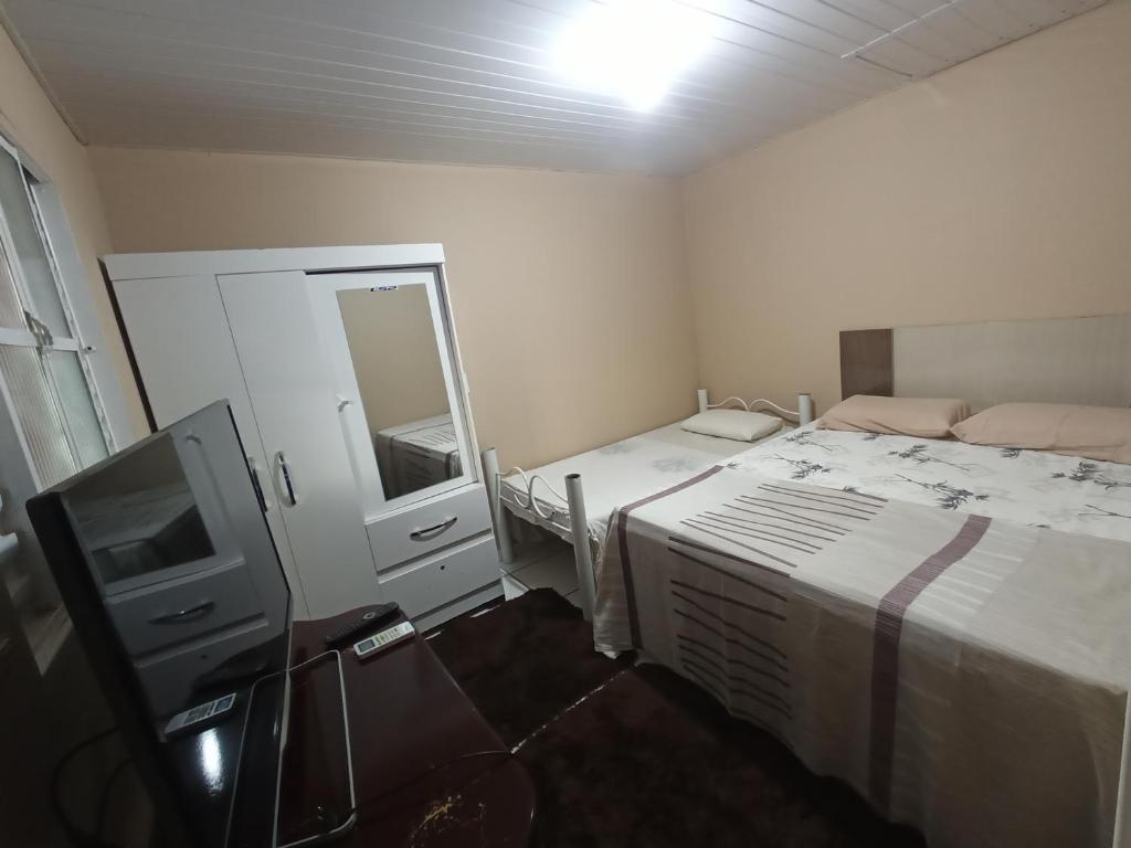 a small bedroom with a bed and a tv at Casa inteira, Quarto p 3 pessoas com Ar, Sala Cozinha,Wifi,Garagem Coberta in Foz do Iguaçu