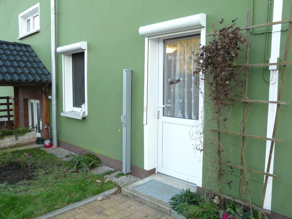 una casa verde con una puerta blanca y una vid en Ferienwohnung mit Seeblick - b46412, en Lychen