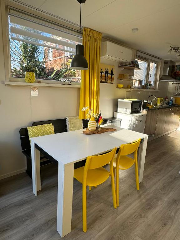 a kitchen with a white table and yellow chairs at Coastal Dreaming in Egmond aan Zee