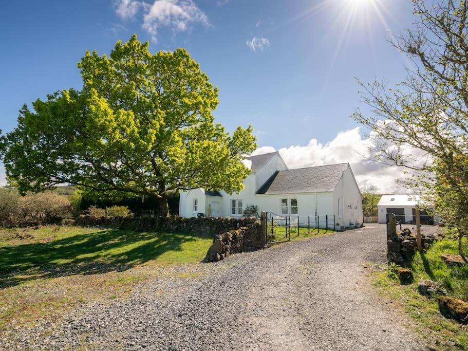 a white house with a tree and a gravel road at Deerside, Tobermory in Tobermory