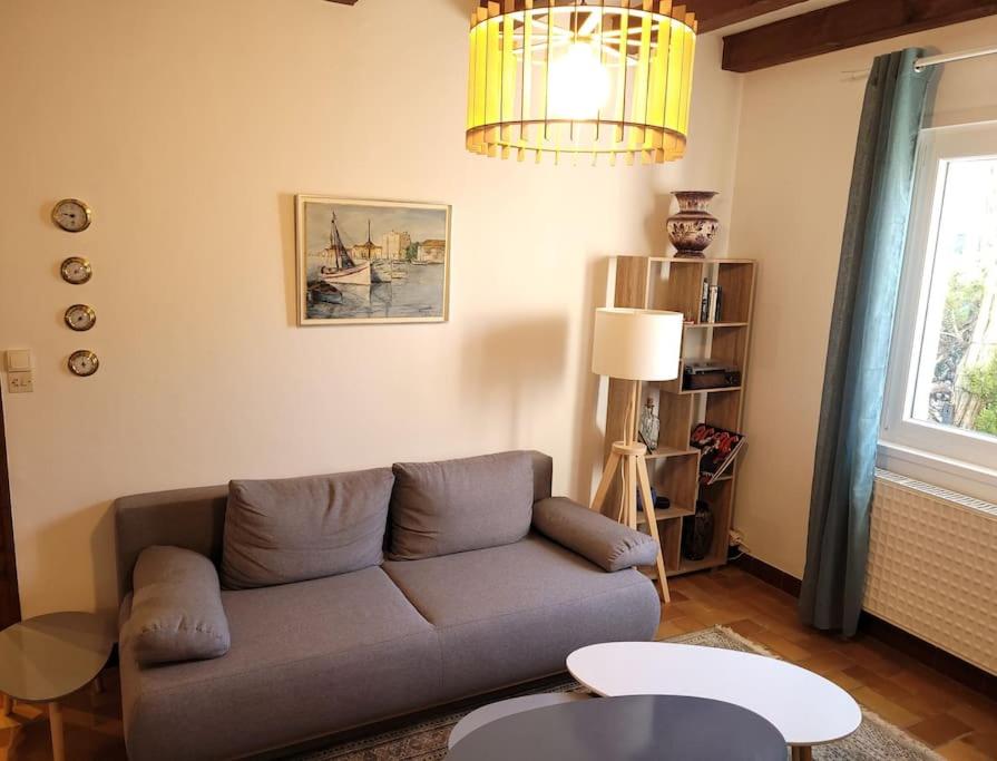 a living room with a couch and a chandelier at Côté Mer - Les Gîtes de la Côte d'Amour in Le Croisic