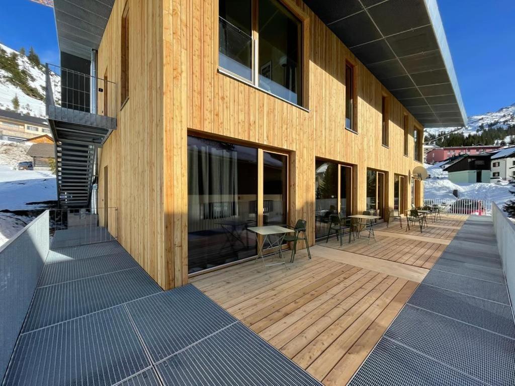 un edificio con una terraza de madera en la nieve en Hideaway Planneralm operated by JUFA Hotels en Planneralm