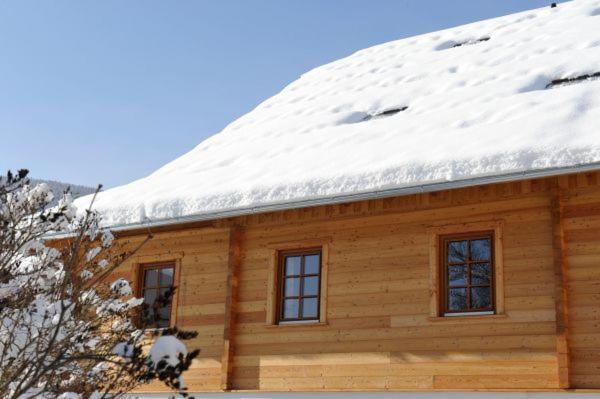 a log cabin with snow on the roof at Stranach Appartements in Sankt Michael im Lungau