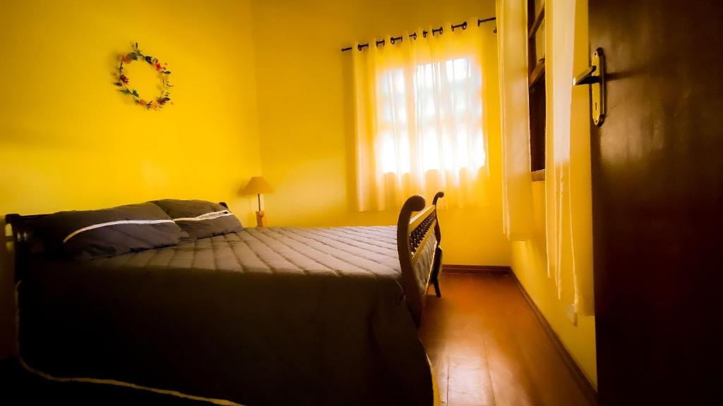 a yellow bedroom with a bed and a window at Chalé com vista incrível in São Roque