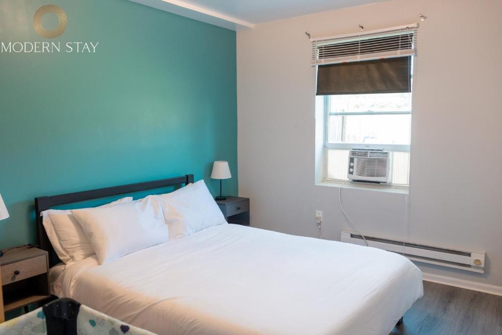 a bedroom with a white bed and a blue wall at Sapphire Suite Near NYC in Bayonne