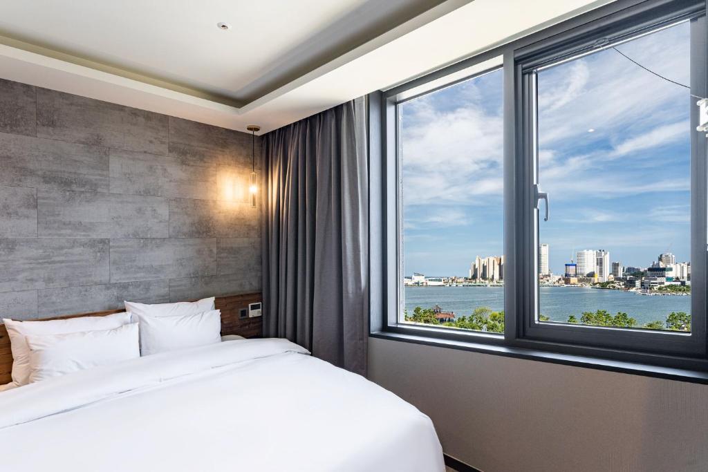 a bedroom with a bed and a large window at Sokcho Business Hotel CAMEL in Sokcho