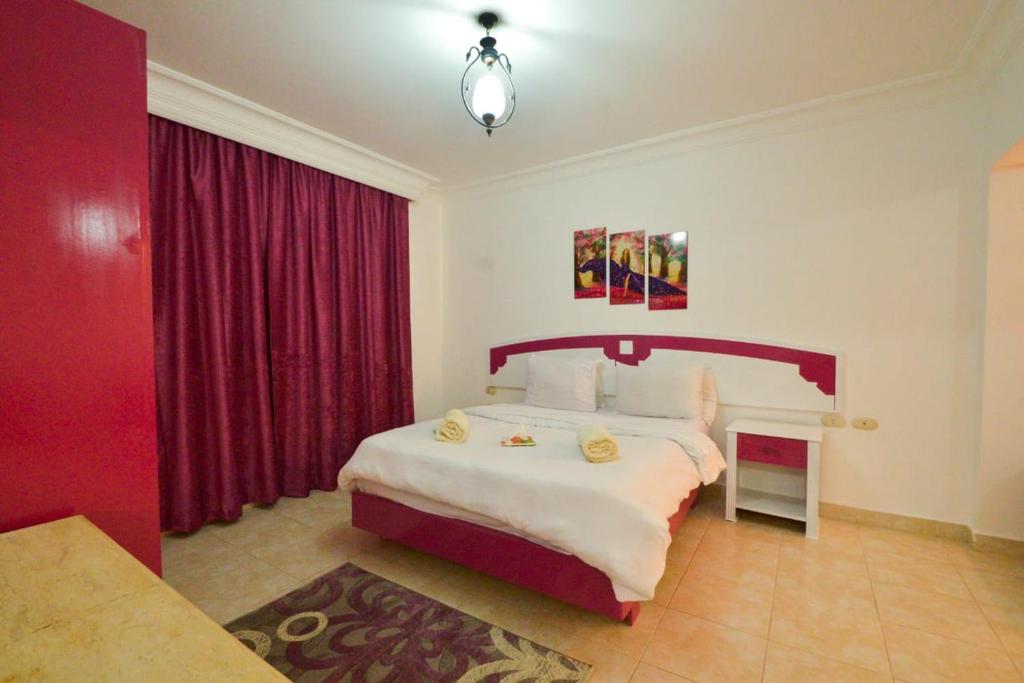 - une chambre avec un grand lit et des rideaux rouges dans l'établissement Delta Sharm, à Charm el-Cheikh
