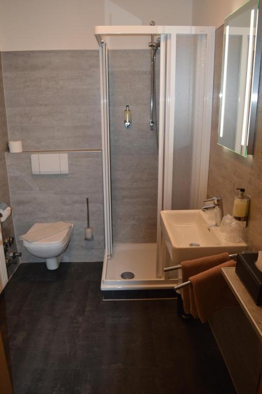 a bathroom with a shower and a toilet and a sink at Hotel Belvedere in Warnemünde
