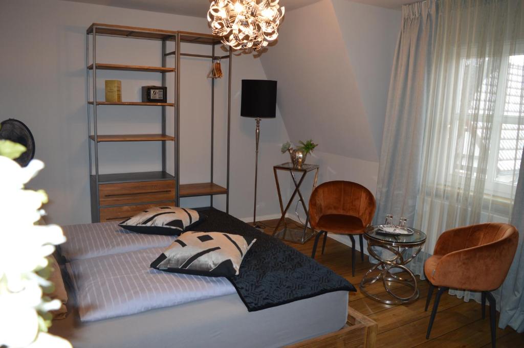 a bedroom with a bed with two chairs and a chandelier at Hotel Belvedere in Warnemünde