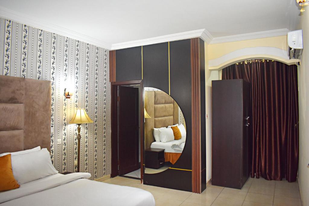 ポートハーコートにあるDAVIS HOTEL AND SUITESのベッドと鏡が備わるホテルルーム