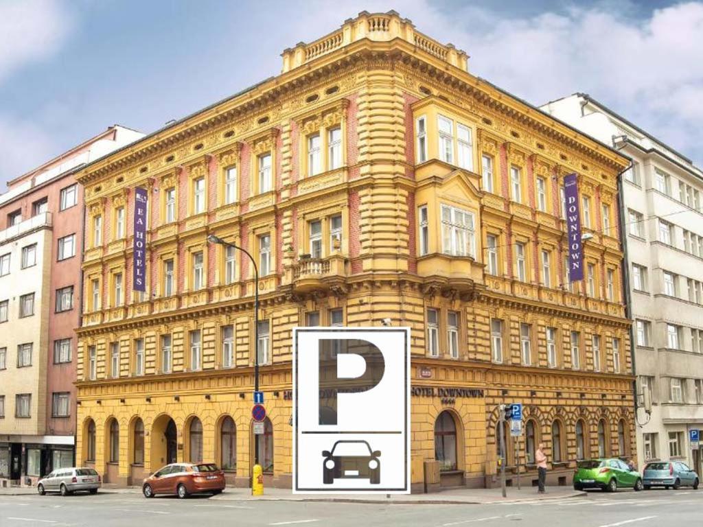 un gran edificio amarillo con una señal de estacionamiento delante de él en EA Hotel Downtown en Praga