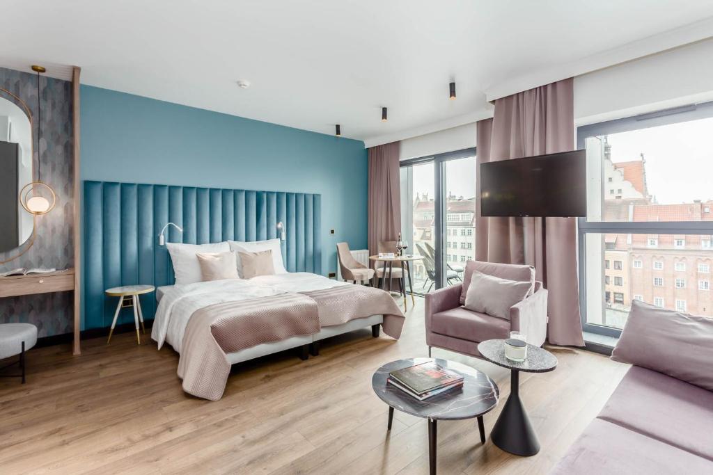 um quarto de hotel com uma cama e um sofá em Deo Apartamenty na Wyspie Spichrzów em Gdansk