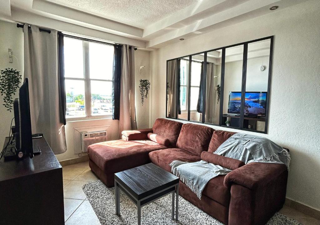 een woonkamer met een bruine bank en een tv bij Son de Metro Apartment / near Distrito T-Mobile in San Juan