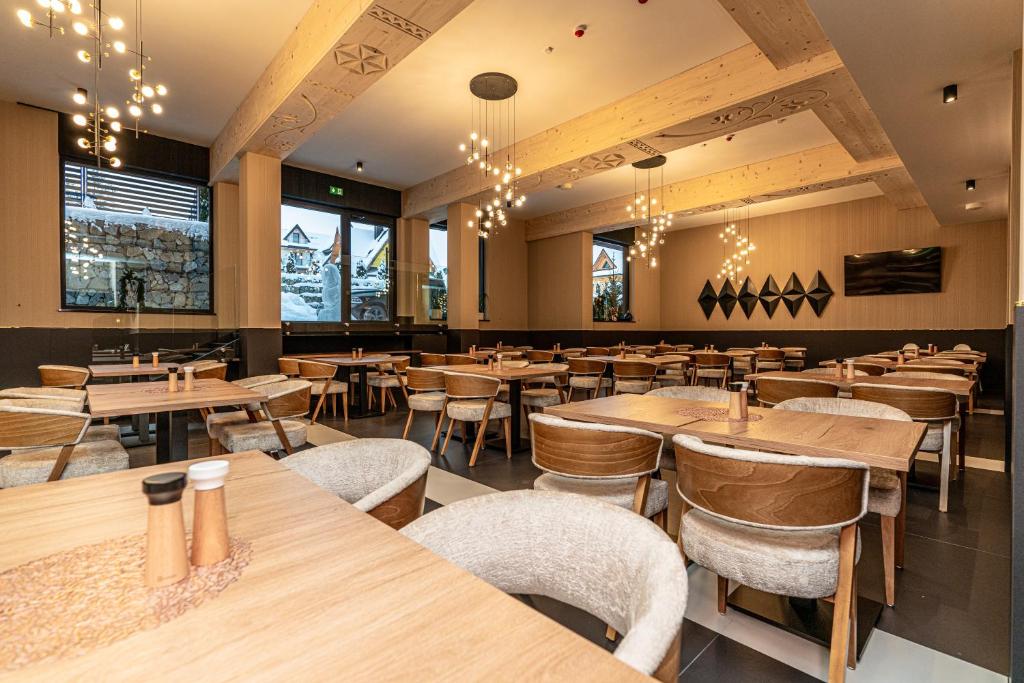 Large restaurant dining room with wooden tables, upholstered chairs, exposed beams and hanging pendant lights