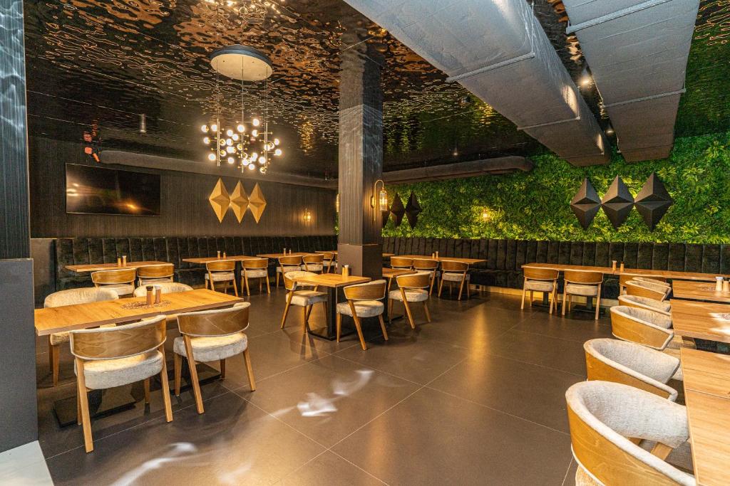 Cozy dining area featuring wooden tables, velvet banquette seating and a vertical green plant wall