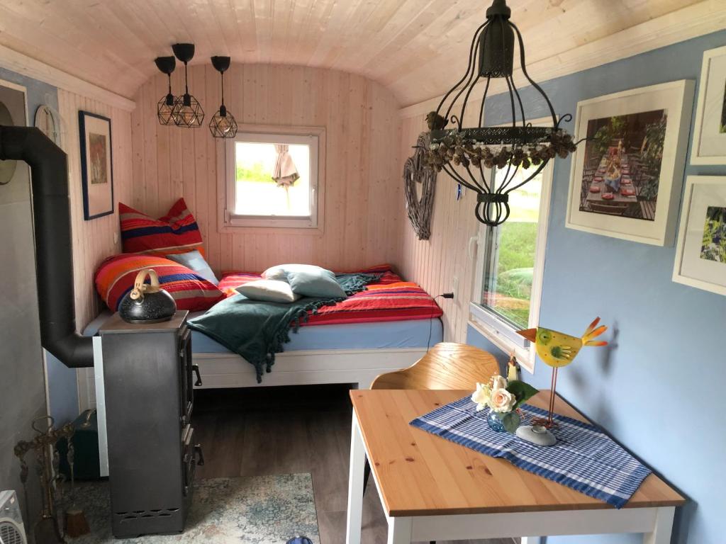 Dormitorio pequeño con cama y mesa en Schäferwagen im Auszeithof, en Niederfrohna