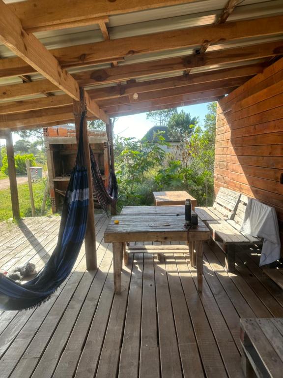 a hammock and a bench on a wooden deck at dream house in Punta Del Diablo