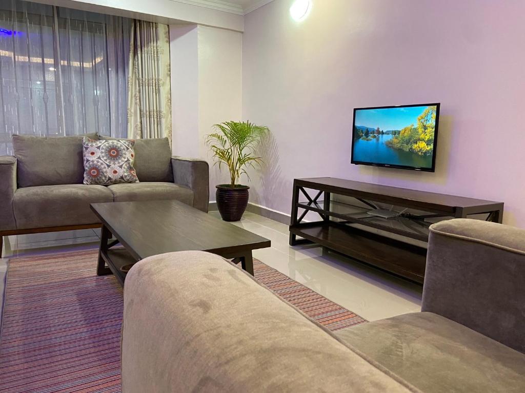 Midtown Executive Suites With Balcony, King Bed في ناكورو: غرفة معيشة مع كنبتين وتلفزيون بشاشة مسطحة