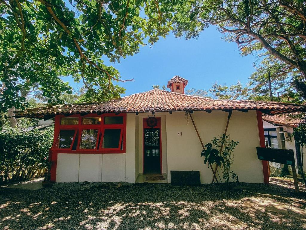 een klein wit huis met een rode deur bij Buzios Praia Caravelas cs 11 in Baía Formosa
