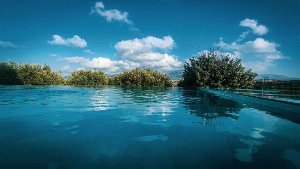 a large pool of blue water with trees in the background at Villa Thea sitia in Sitia