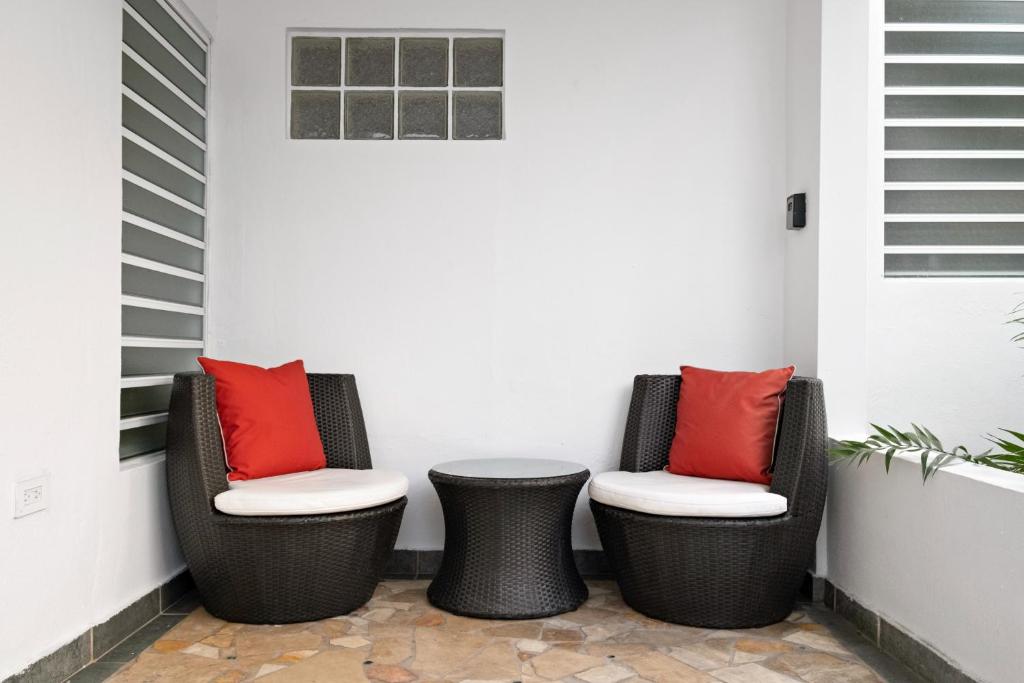 2 Stühle und ein Tisch auf einer Veranda mit roten Kissen in der Unterkunft Prime Location at Condado Beach 1br 1ba - Apt 8 in San Juan