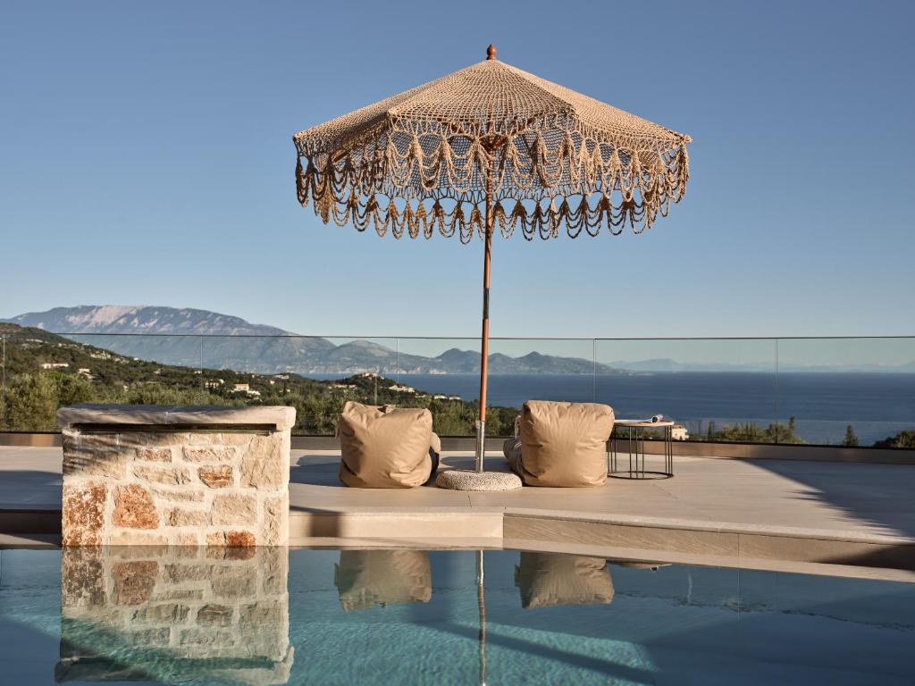 an umbrella and chairs next to a swimming pool at Ocean Luxury Villas in Volimes