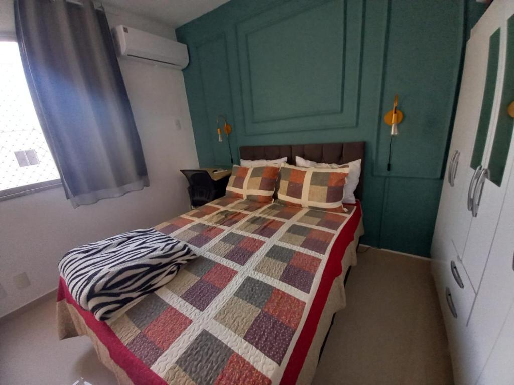 um quarto com uma cama com uma colcha em Apartamento próximo da praia em São José de Ribamar