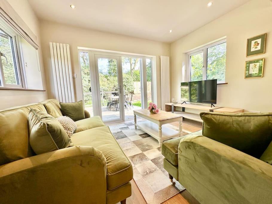 a living room with two couches and a flat screen tv at Greenacre Lodge - cosy, dog-friendly rural home with private garden in Redgrave