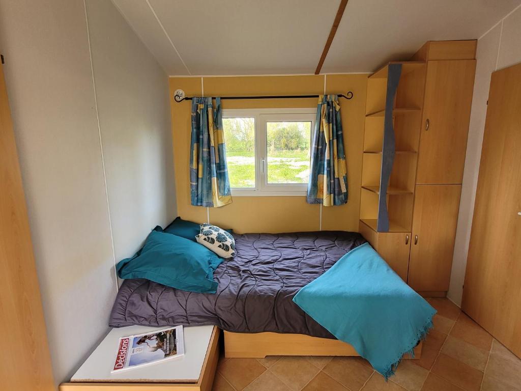a small bedroom with a bed and a window at Camping les 2 salamandres in Arces-sur-Gironde