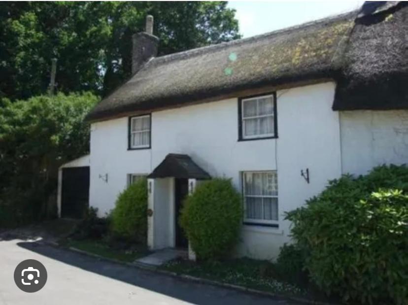 a white house with a thatched roof at Vinny Cottage in Owermoigne