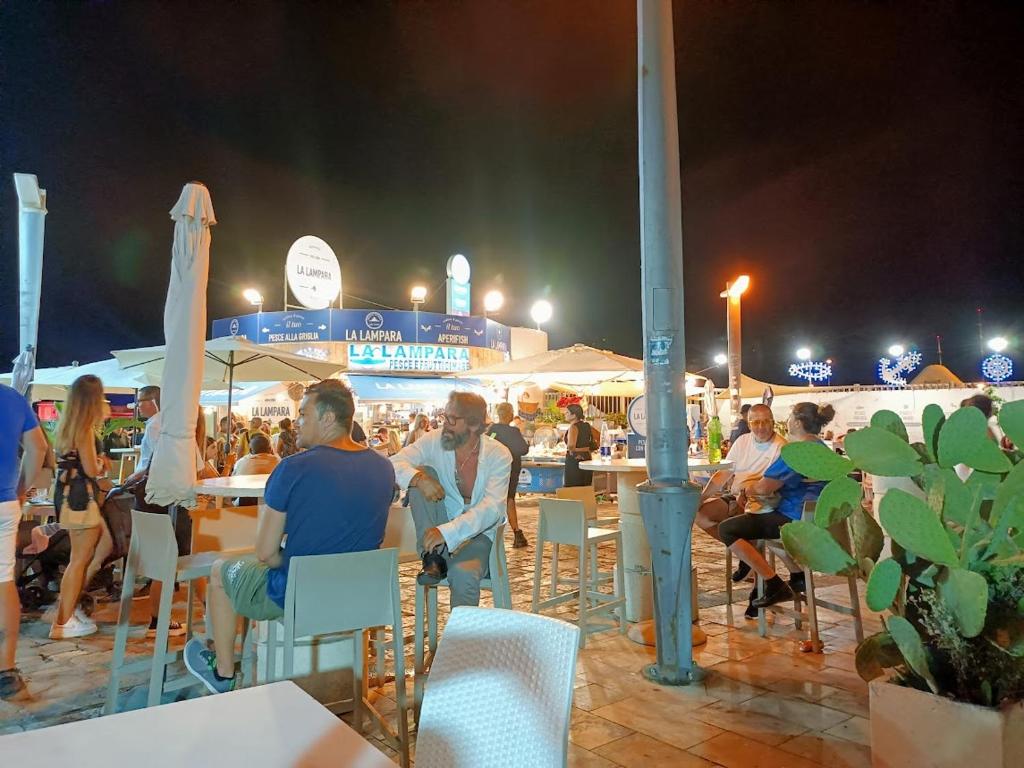um grupo de pessoas sentadas em mesas na praia à noite em Betty casa vacanze em Aradeo