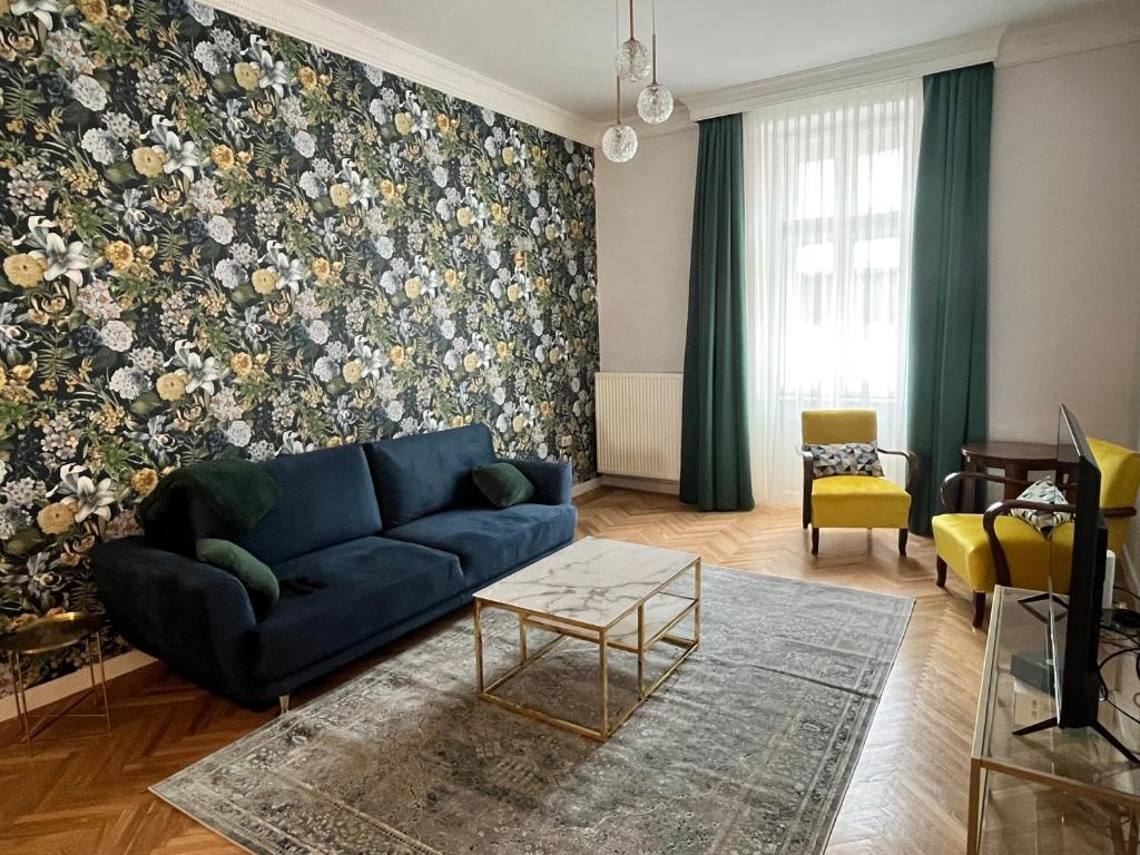 ein Wohnzimmer mit einem blauen Sofa und einer Blumenwand in der Unterkunft Ady1 Apartment in Kaposvár