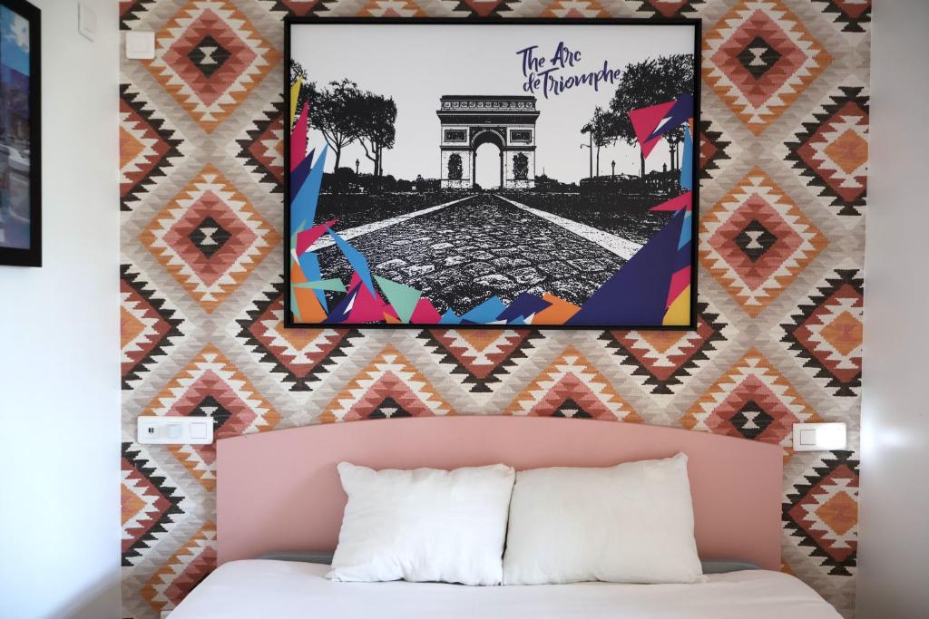 a wall with a picture above a bed with a white bed sidx sidx at St Christopher's Inn Paris - Canal in Paris
