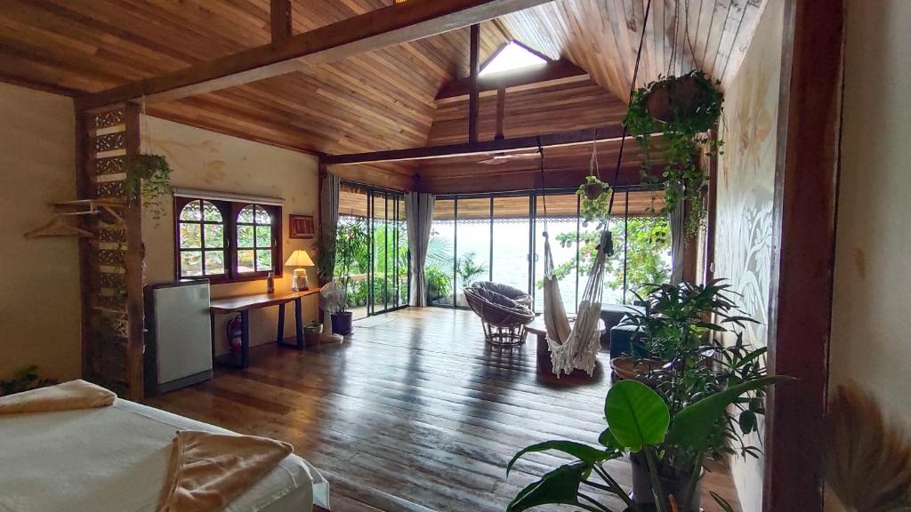 a living room with wooden ceilings and a room with plants at Why Nam Beach in Haad Yuan