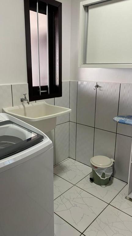 La salle de bains blanche est pourvue d'un lavabo et de toilettes. dans l'établissement Summer Beach Paiquere, à Araranguá