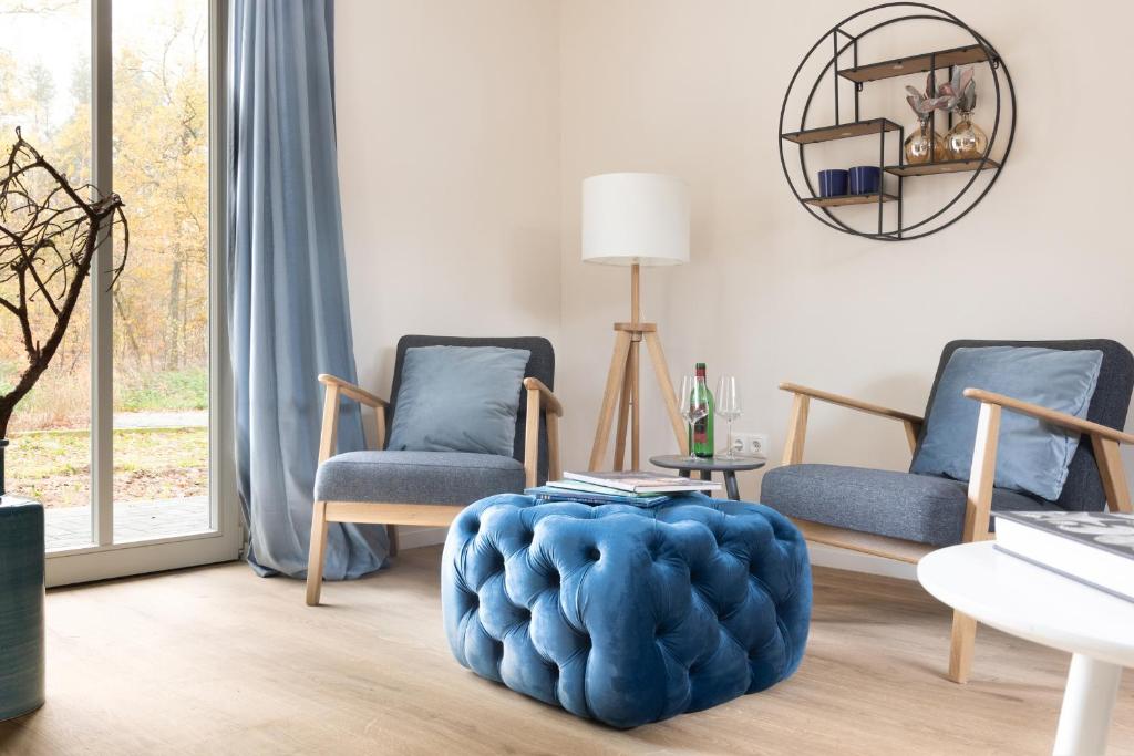 a living room with two chairs and a blue ottoman at Ferienwohnungen in Wald und Flur - Wohnung Wald in Lüder