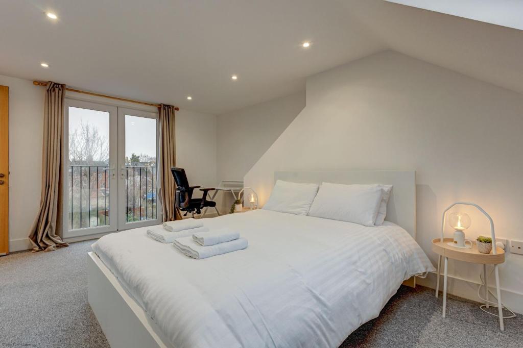 a white bedroom with a large bed and a window at Henley Street Townhouse in Oxford