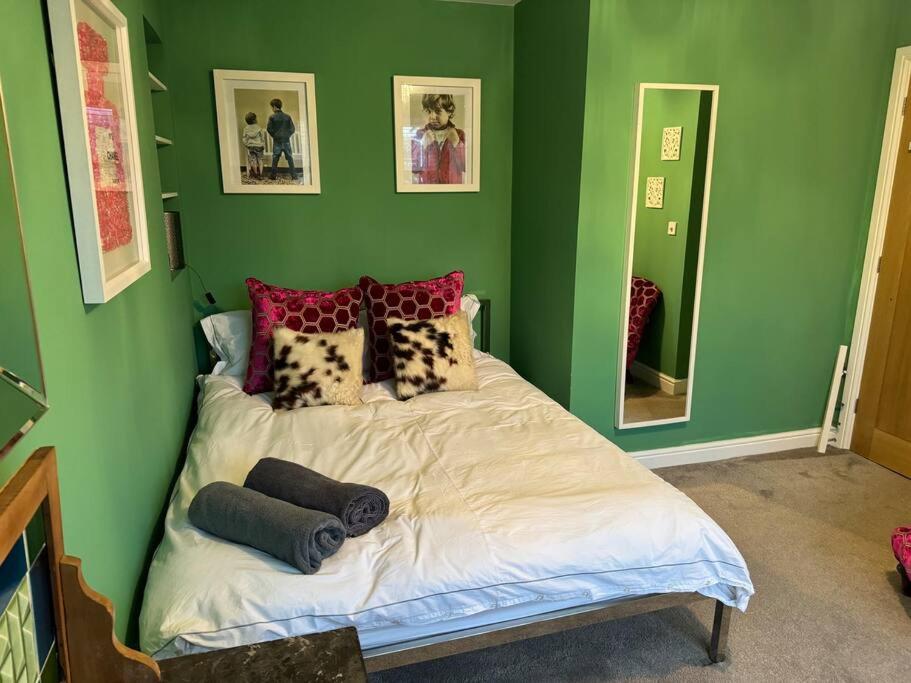 um quarto com paredes verdes e uma cama com almofadas em Izzy's house em Deysbrook