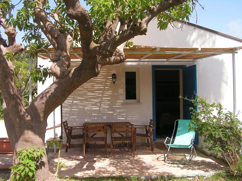 eine Terrasse mit einem Tisch und Stühlen unter einem Baum in der Unterkunft Appartamento In Villa Al Mare - Baia di Arcile in Brucoli