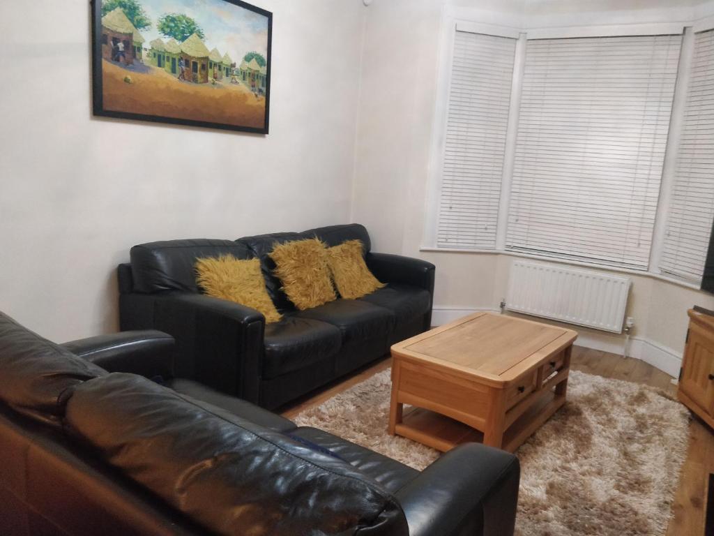 a living room with a leather couch and a coffee table at Whites Place in Slades Green
