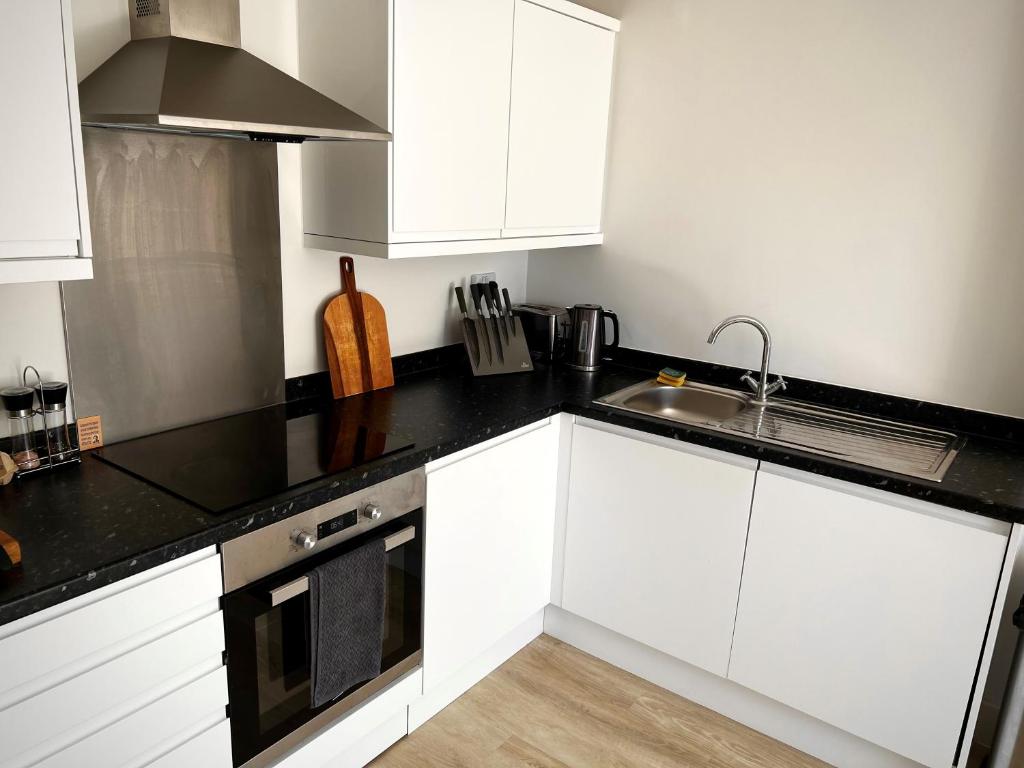 a kitchen with white cabinets and a black counter top at No hidden costs! - 1 Bedroom Apartment - York in York
