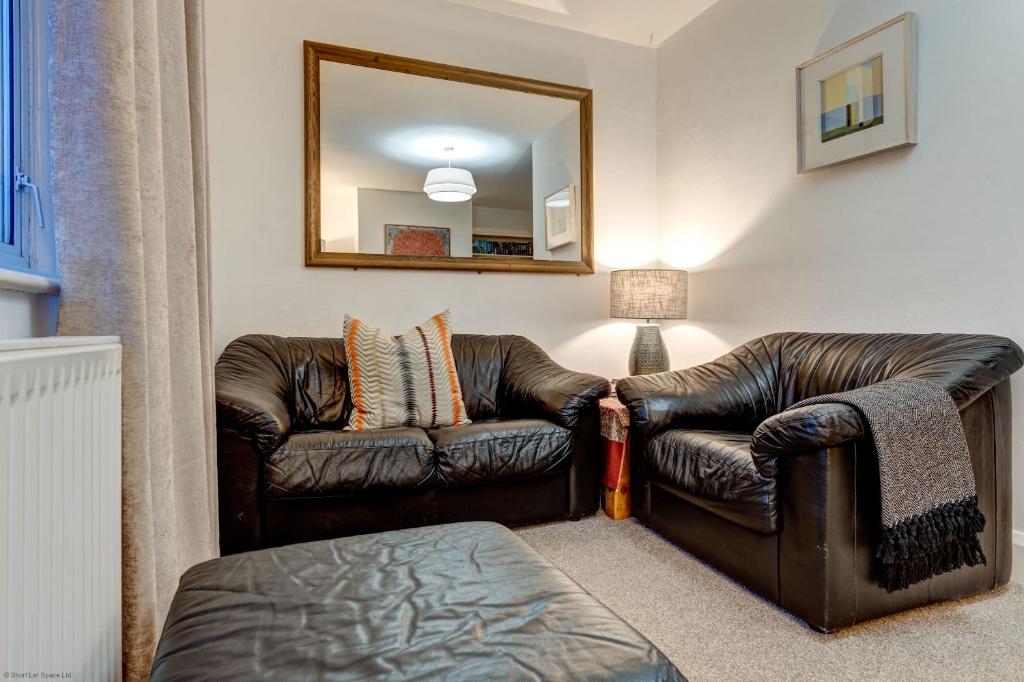 a living room with a leather couch and a mirror at The Oxford Meadows in Oxford