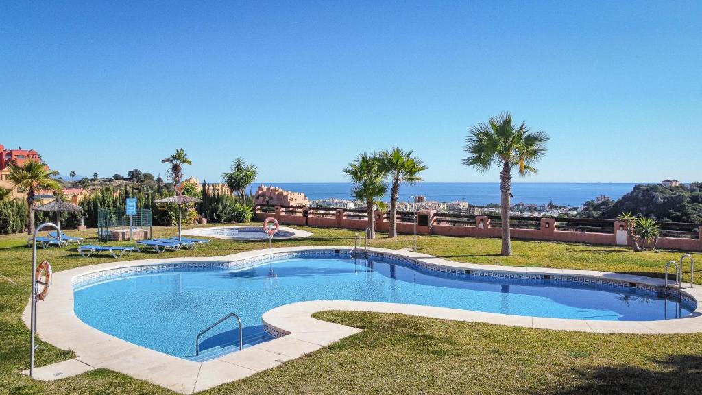 une grande piscine avec des palmiers et l'océan dans l'établissement 7 Apartment near Duquesa Port Manilva Coto Real, à Manilva