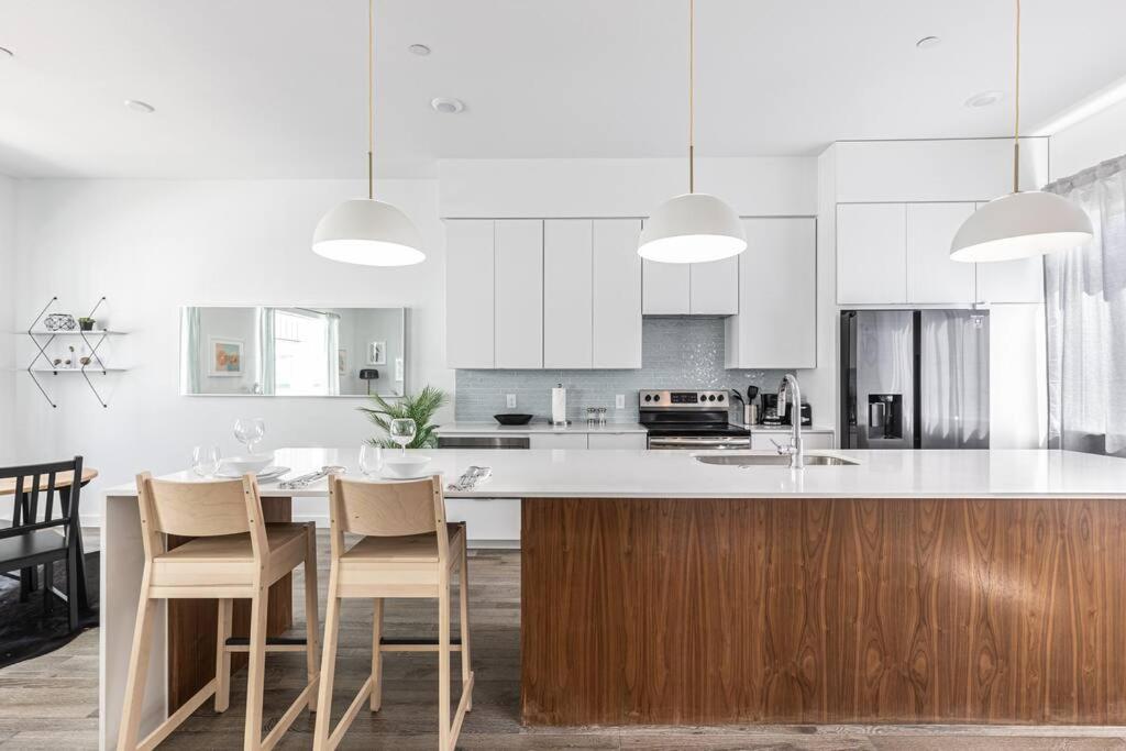 uma cozinha com armários brancos e uma mesa e cadeiras em Amazing Location Modern 2-Bed Townhome em Dallas