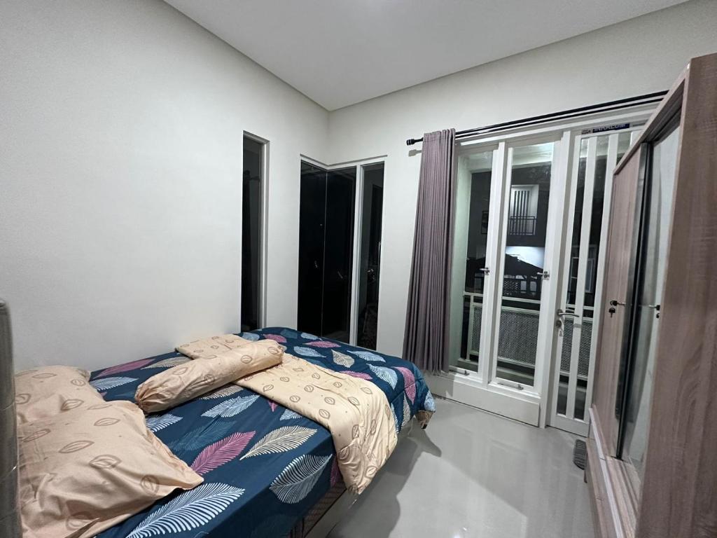 um quarto com uma cama e uma grande janela em Villa Sunrise F1 em Malang