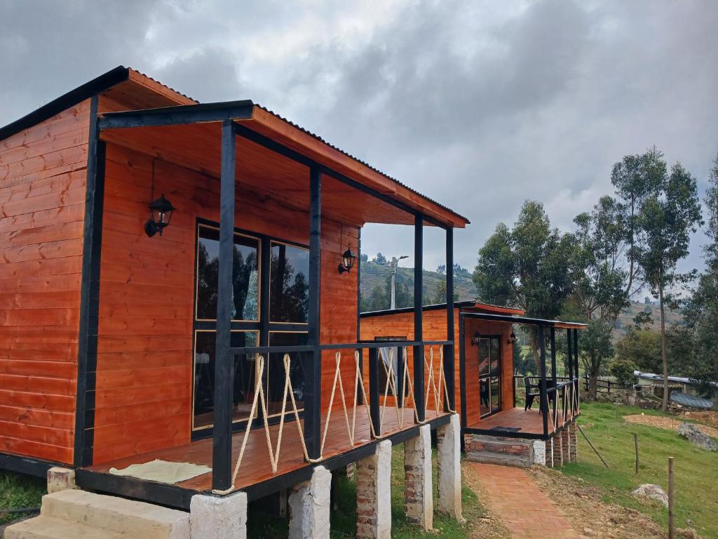 a wooden house with glass windows on a field at Cabañas finca las acacias in Guatavita