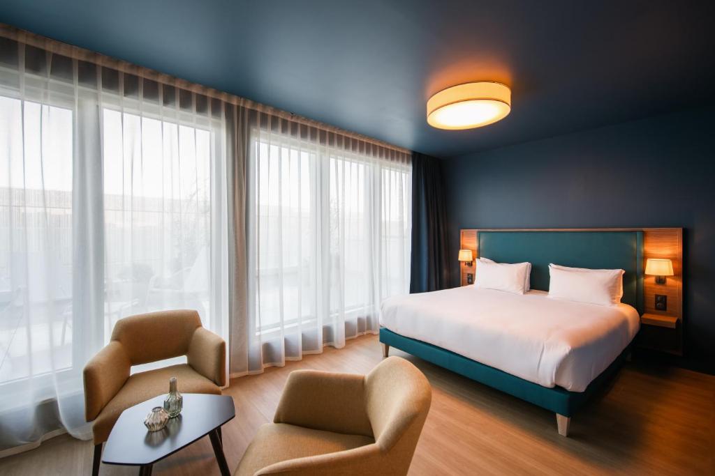 pokój hotelowy z łóżkiem i 2 krzesłami w obiekcie Hôtel de la Cité w mieście Nantes